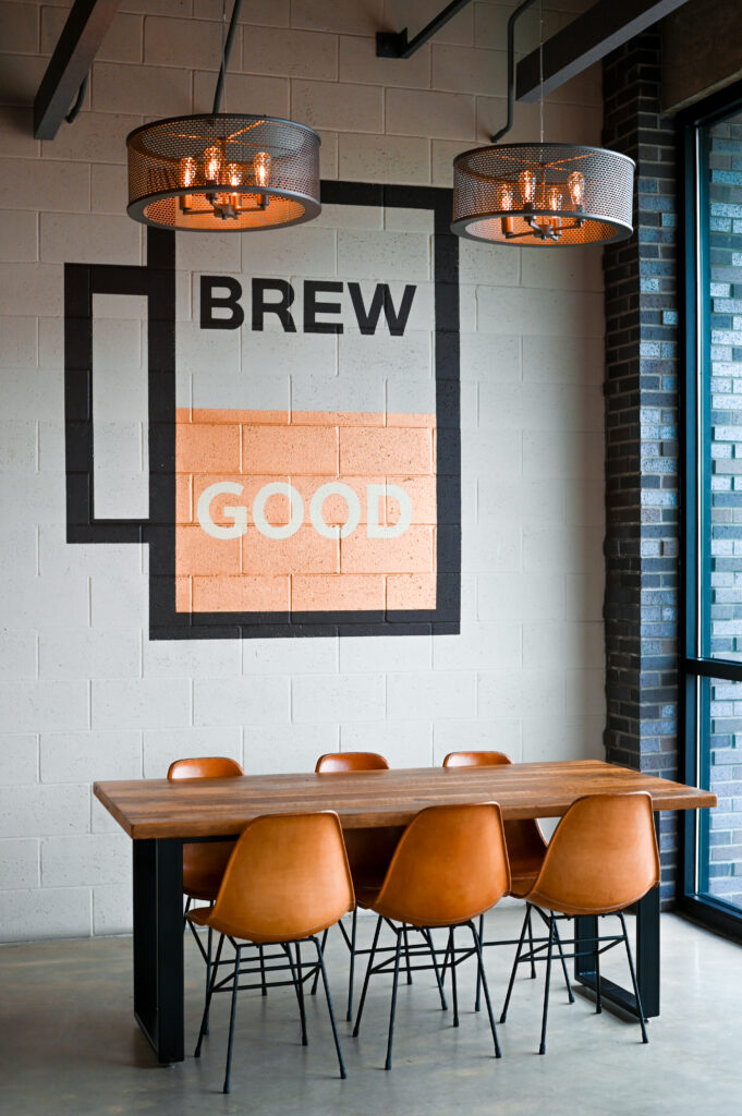 Modern brewery interior in St. Pete with orange chairs and a wall sign that says Brew Good, photographed for brewery branding and hospitality marketing.